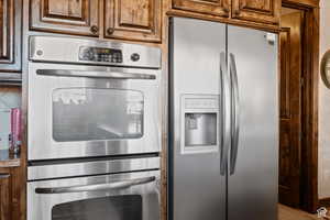 Kitchen with appliances with stainless steel finishes, wood finished floors, and brown cabinets