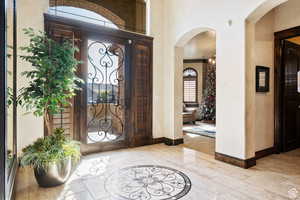 Entryway featuring inlaid floor details, arched walkways, and wood finished floors