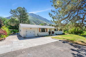 Ranch-style home with concrete driveway, a garage, a mountain view, brick siding, and a front lawn