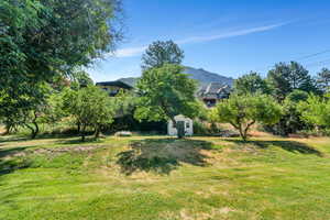 View of green lawn featuring a mountain view and an outdoor structure