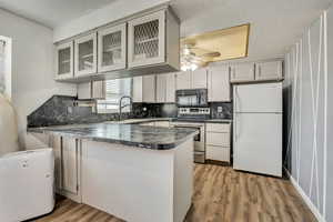 Kitchen featuring dark countertops, freestanding refrigerator, electric stove, a textured ceiling, and backsplash