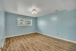 Empty room featuring wood finished floors and a textured ceiling