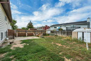 Fenced backyard with a storage unit, a patio, and a residential view