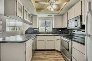 Kitchen featuring a peninsula, appliances with stainless steel finishes, dark countertops, backsplash, and a textured ceiling