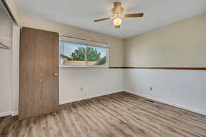 Unfurnished bedroom with wood finished floors, a closet, and a ceiling fan
