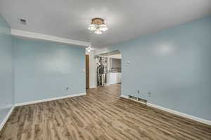 Spare room featuring wood finished floors, a textured ceiling, separate washer and dryer, and arched walkways