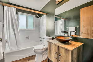 Full bath with shower / tub combo, vanity, and wood finished floors