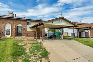 View of front of home with a patio area, a front yard, brick siding, driveway, and solar panels