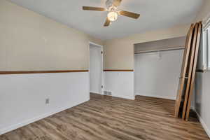 Unfurnished bedroom with wood finished floors, a closet, and a ceiling fan