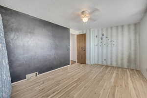 Unfurnished room featuring light wood-type flooring, a textured ceiling, and ceiling fan