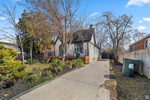 View of side of property featuring an outdoor structure, a chimney, a wooden deck, a garage, and driveway