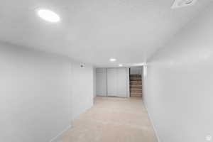 Finished basement featuring a textured ceiling, carpet, stairway, and recessed lighting