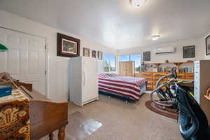 Carpeted bedroom with freestanding refrigerator and a textured ceiling