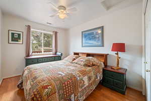 Bedroom with attic access, wood finished floors, and ceiling fan
