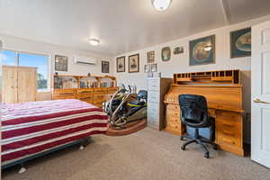 Bedroom with carpet flooring, a desk, and a wall unit AC