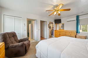 Bedroom with a ceiling fan, a wall unit AC, and two closets