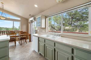Kitchen featuring green cabinetry, lofted ceiling, dishwasher, pendant lighting, and recessed lighting
