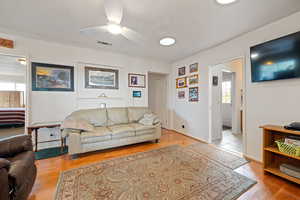 Living room with light wood-type flooring and ceiling fan