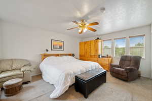 Carpeted bedroom with a ceiling fan and a textured ceiling