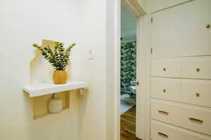 Hall with dark wood finished floors and wallpapered walls