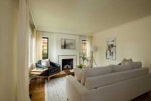 Living room with crown molding, wood finished floors, and a fireplace