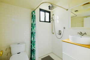Full bath with tile walls, vanity, and a stall shower