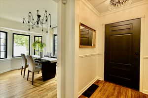 Entryway with a chandelier, light wood-style floors, and crown molding