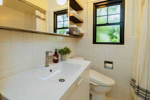 Full bathroom featuring tile walls, vanity, and curtained shower