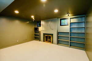 Unfurnished living room featuring a fireplace with flush hearth, carpet floors, and recessed lighting