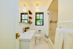 Full bath featuring vanity, shower / tub combo with curtain, tile walls, and light tile patterned flooring