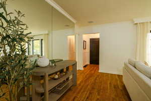 Dining area with ornamental molding and dark wood-style floors