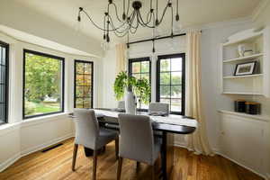 Dining area featuring ornamental molding, wood finished floors, and a chandelier