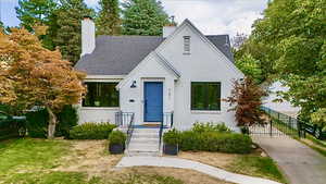 View of front of home featuring a chimney, brick siding, and a shingled roof