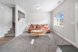 Carpeted living area with stairs and baseboards