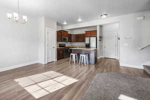 Kitchen with a kitchen breakfast bar, stainless steel appliances, a kitchen island with sink, a chandelier, and decorative light fixtures