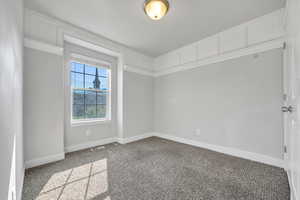 Carpeted spare room featuring baseboards