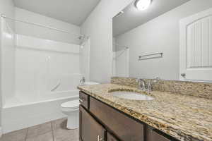 Full bath with bathing tub / shower combination, vanity, and light tile patterned flooring