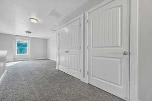 Unfurnished bedroom featuring carpet flooring, attic access, and a closet