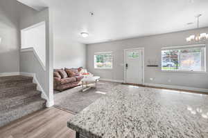 Living room featuring a chandelier, light wood-style flooring, stairway, and a textured ceiling