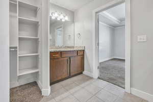 Bathroom featuring vanity, light tile patterned floors, a closet, and crown molding