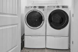 Washroom with light tile patterned flooring and washer and dryer