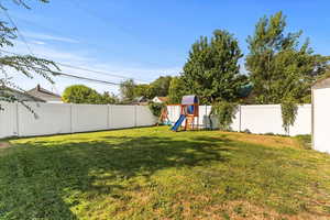 Fenced backyard featuring a playground