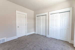 Unfurnished bedroom with two closets and carpet flooring