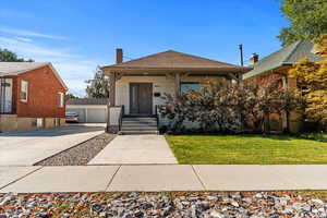View of front of home featuring a chimney, a porch, an outbuilding, a detached garage, and a front lawn