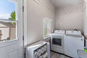 Laundry area with healthy amount of natural light, light wood-style flooring, and washer and dryer