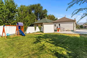 Fenced backyard featuring a patio area, an outdoor structure, and a playground