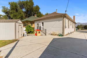 Rear view of house featuring a storage shed, a shingled roof, a mountain view, and a chimney