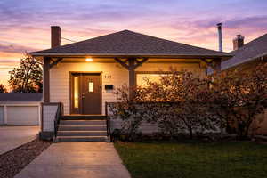 View of front of house with roof with shingles, a chimney, a garage, covered porch, and an outdoor structure