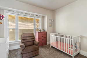 Carpeted bedroom with a nursery area and baseboards
