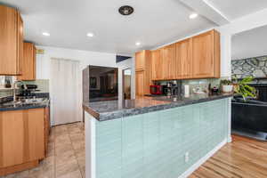 Kitchen featuring tasteful backsplash, a peninsula, recessed lighting, and a stone fireplace
